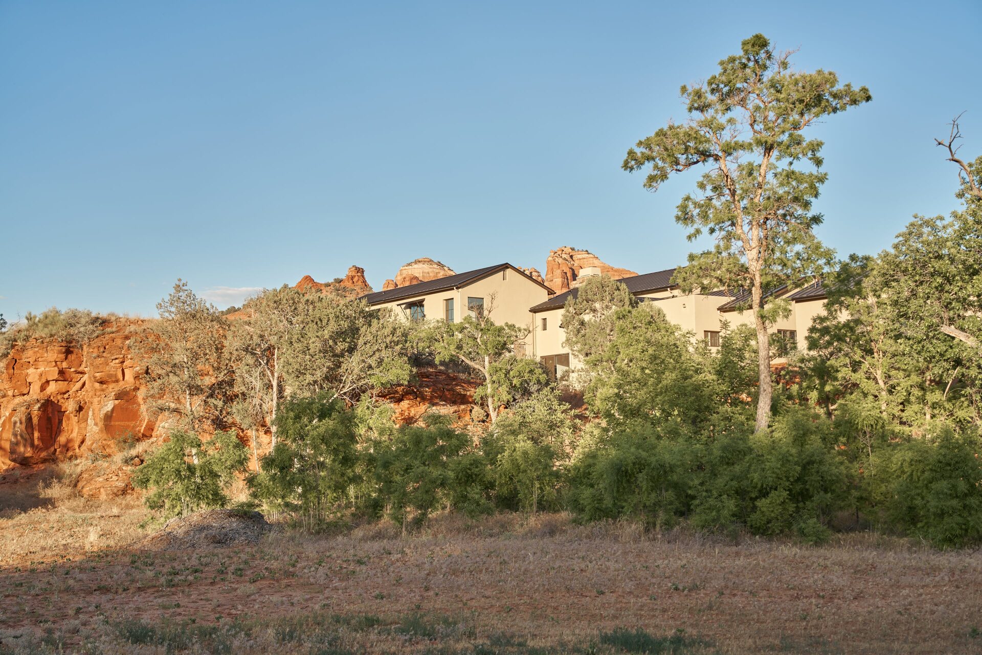 House framed by red rock formation, afternoon